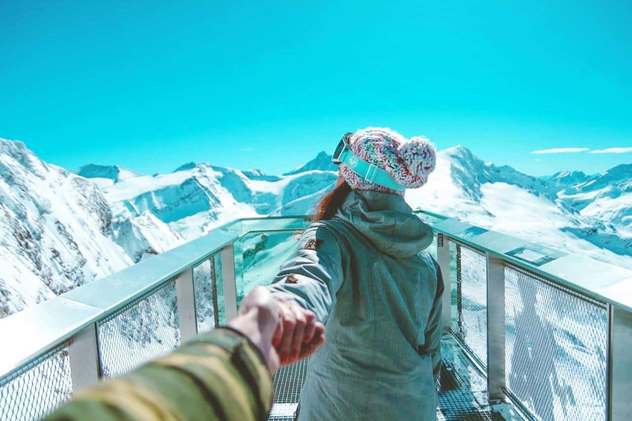 Casal apreciando montanhas cobertas de neve em mirante