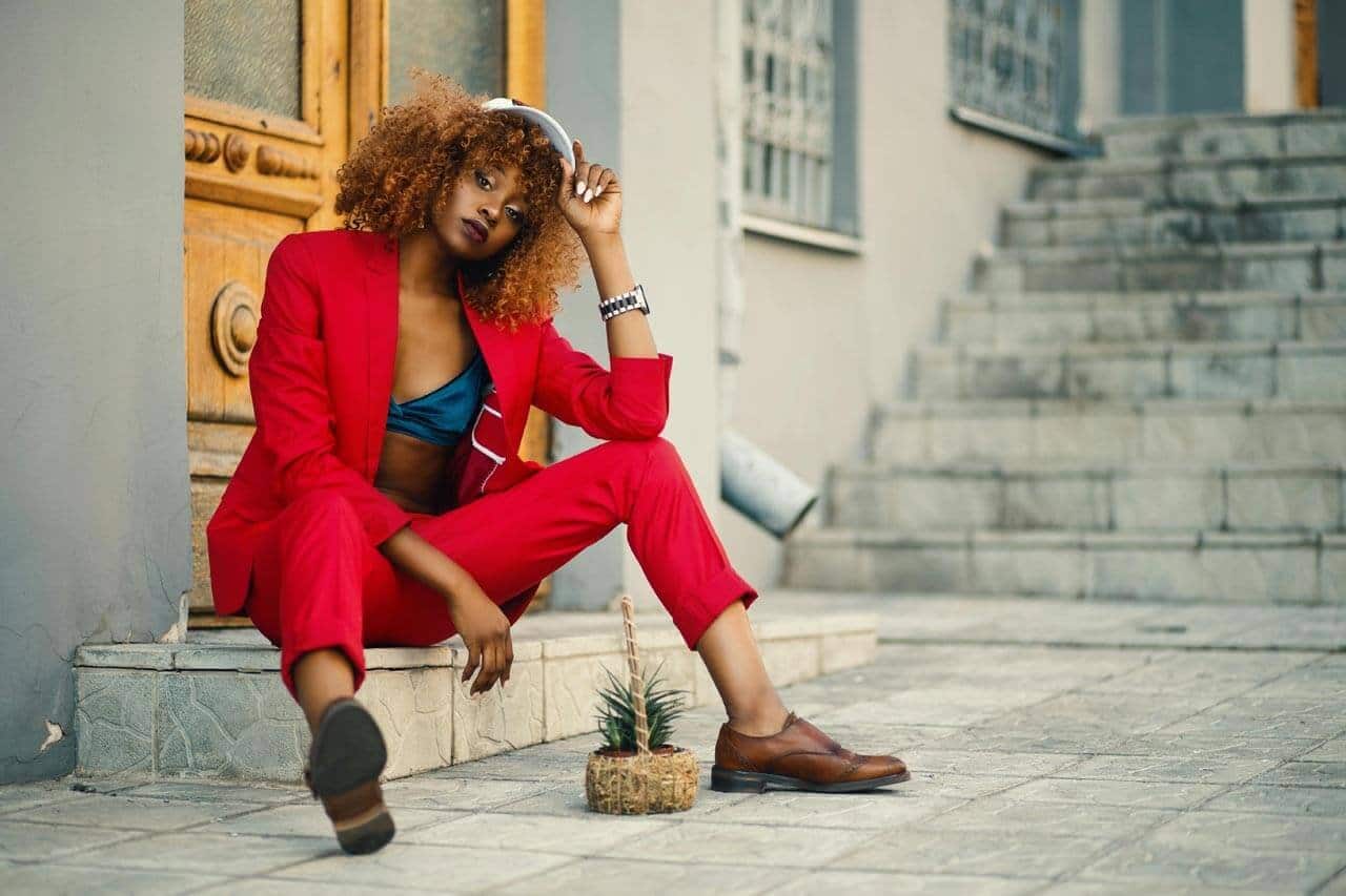 Mulher sentada em escada com terno vermelho estiloso.