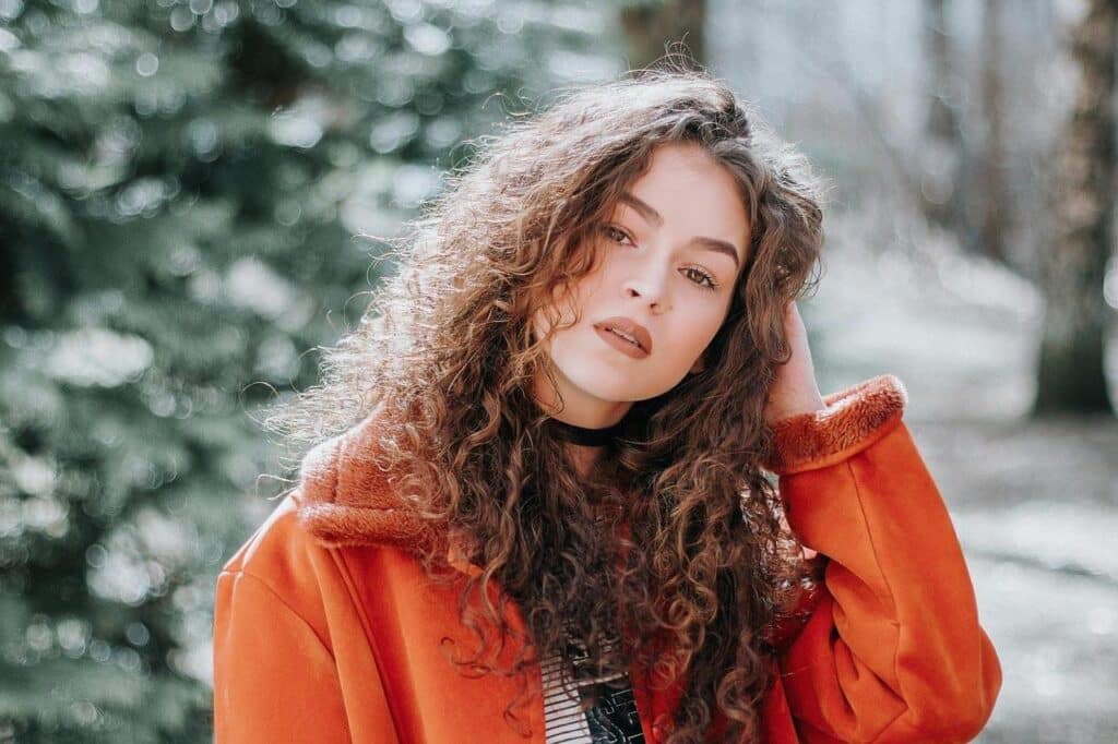 Mulher com casaco laranja em ambiente natural