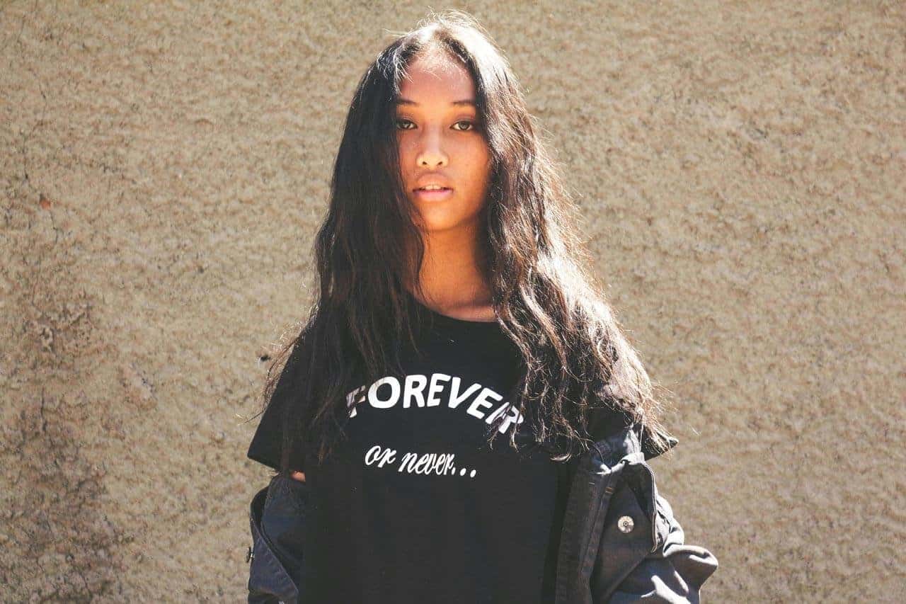 Mulher com camiseta preta, fundo de parede bege.
