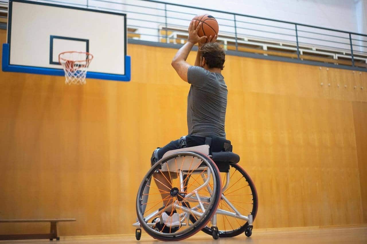 Jogador de basquete em cadeira de rodas arremessando bola.