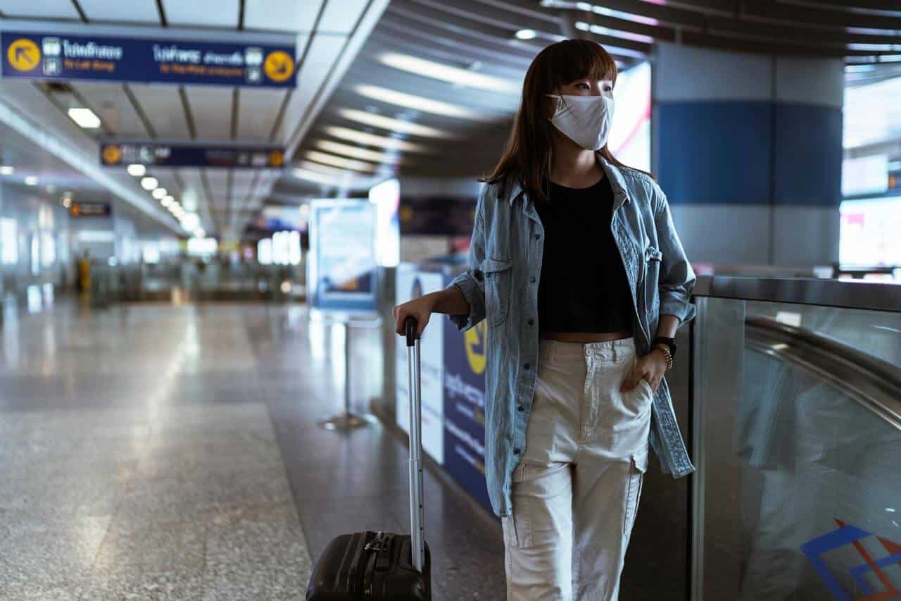 Pessoa com máscara caminhando em aeroporto moderno