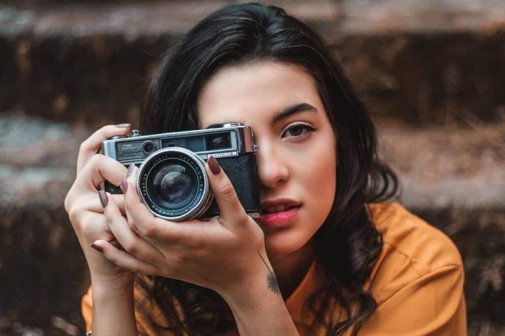 Mulher segurando câmera fotográfica vintage.