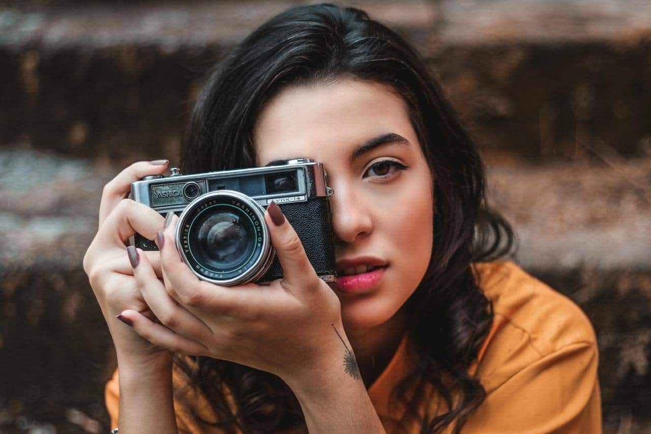 Mulher segurando câmera fotográfica vintage.