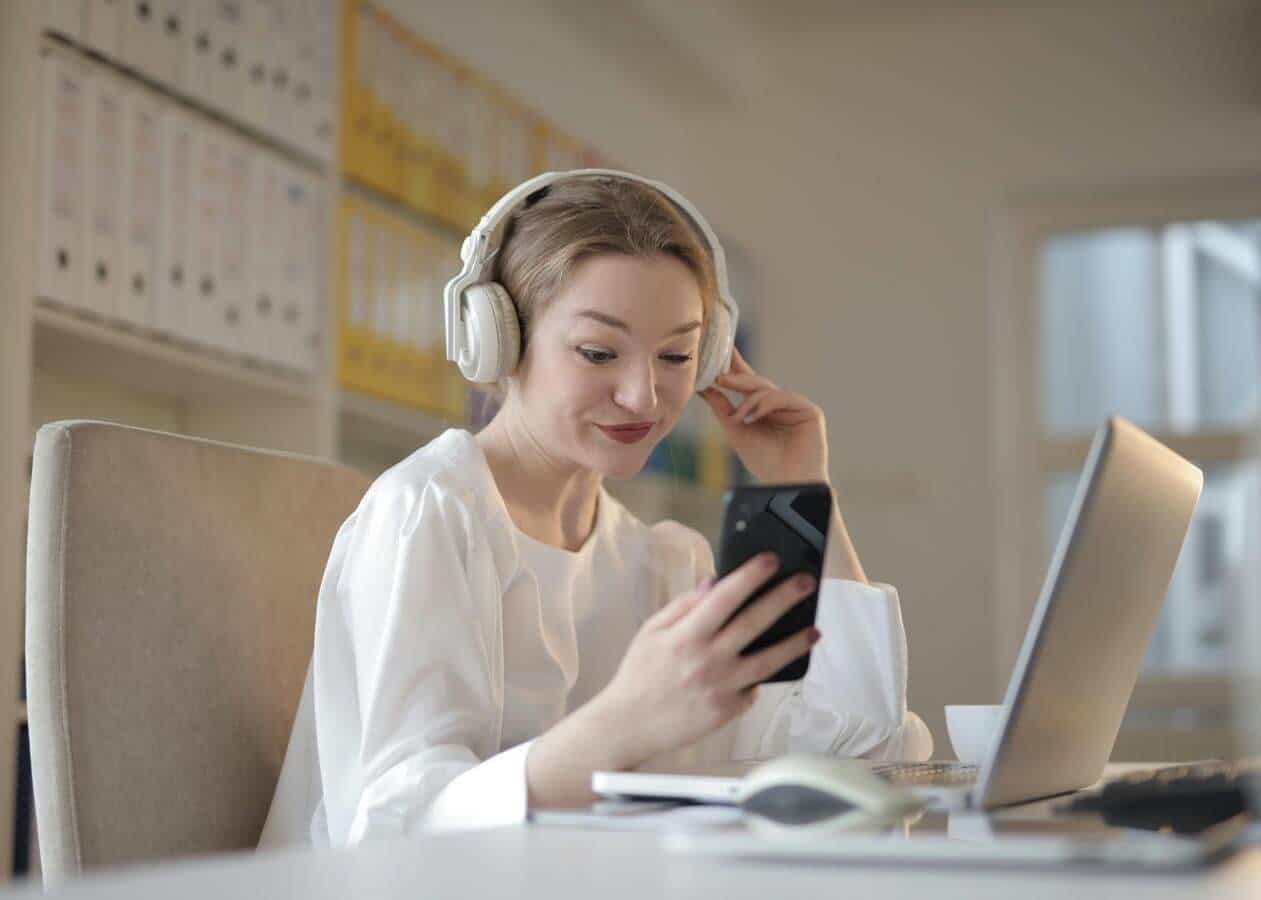 Mulher ouvindo música e usando smartphone no escritório.