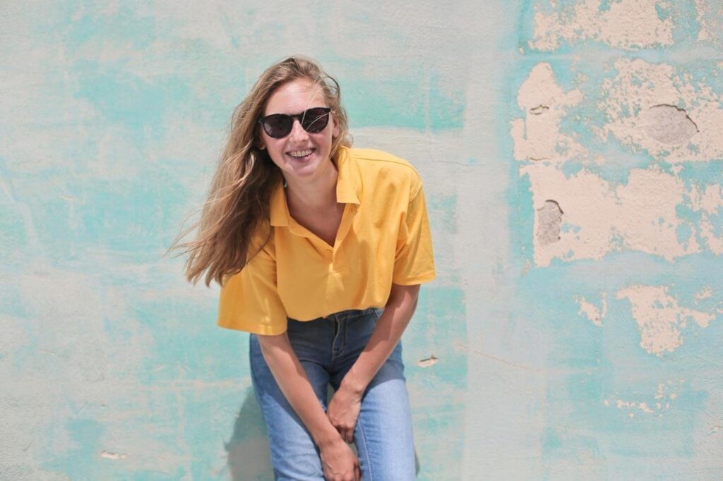 Mulher sorrindo com óculos escuros e camisa amarela