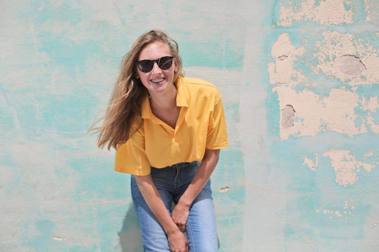 Mulher sorrindo com óculos escuros e camisa amarela
