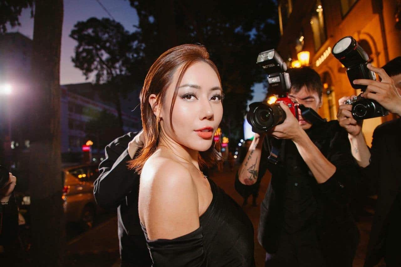 Mulher sendo fotografada por paparazzi à noite