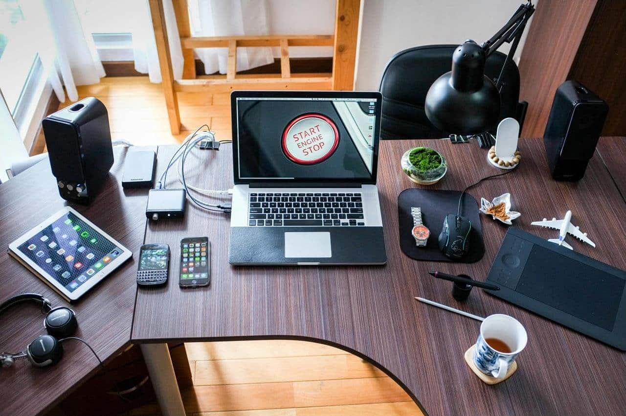 Mesa de trabalho com eletrônicos e laptop aberto.