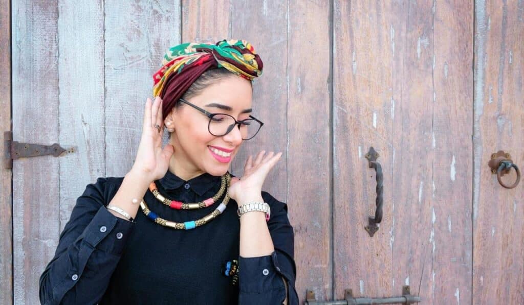 Mulher sorrindo com acessórios coloridos na cabeça.