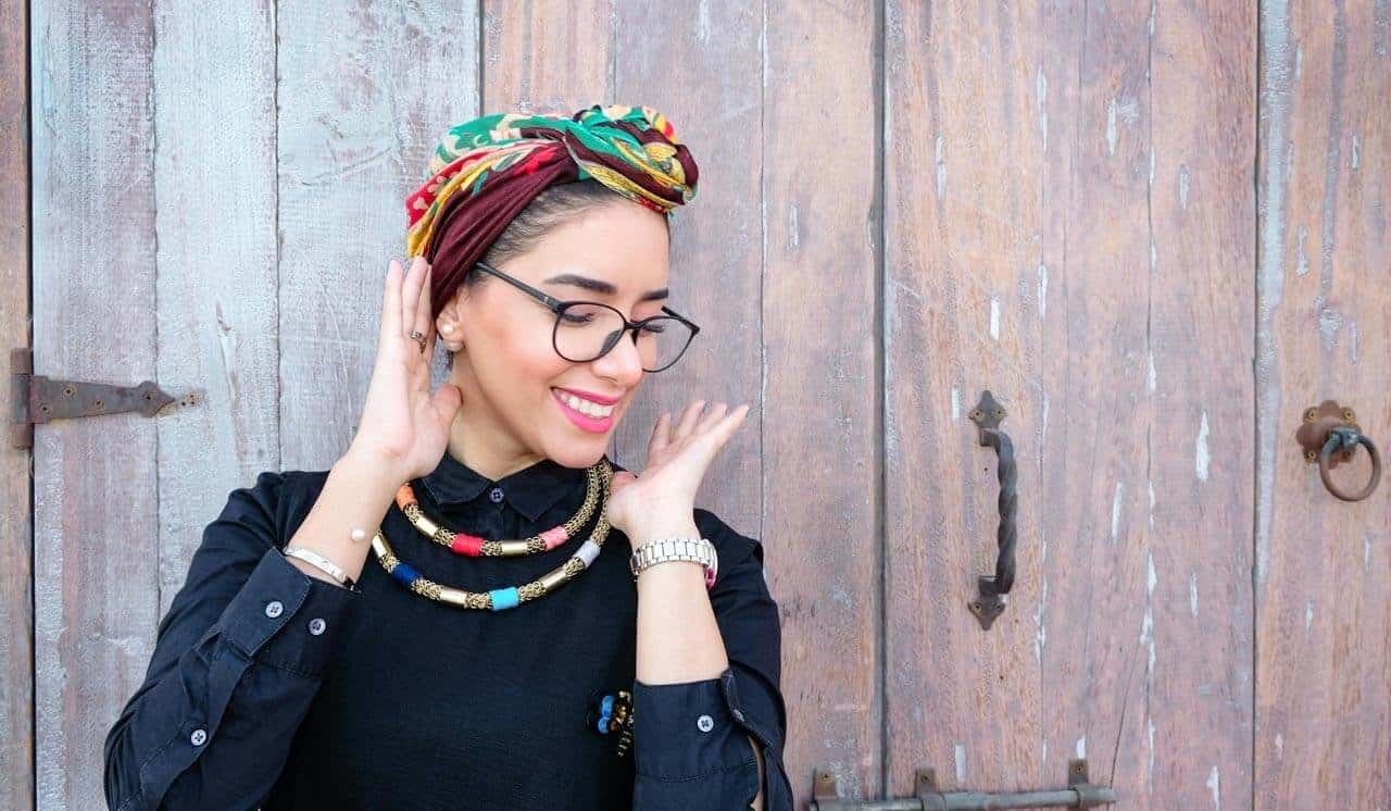 Mulher sorrindo com acessórios coloridos na cabeça.