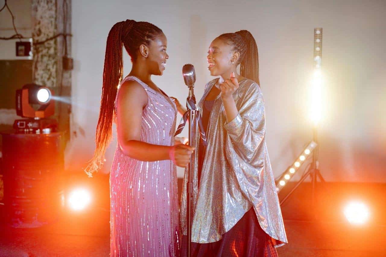 Duas mulheres cantando em palco iluminado.