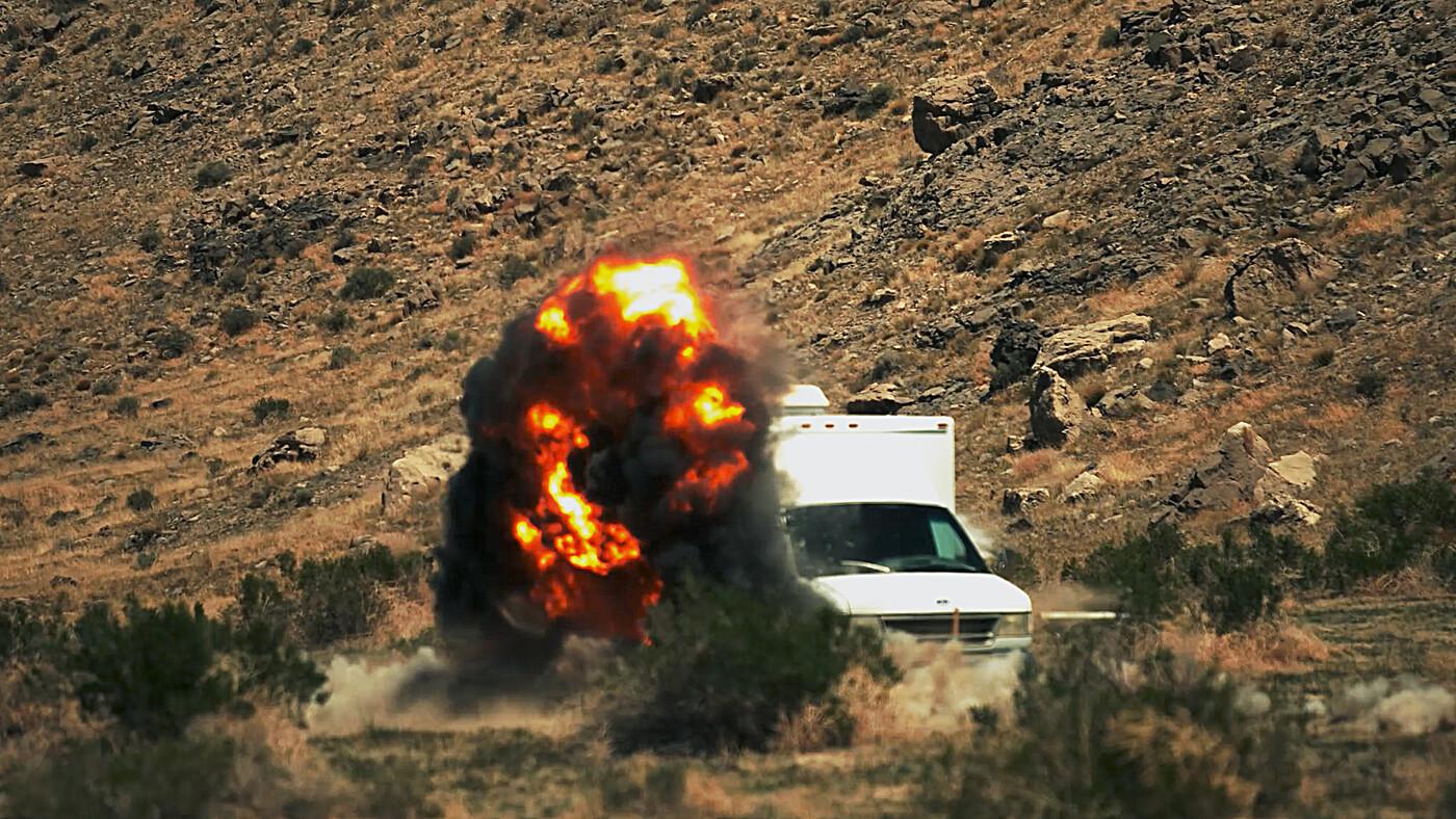 Van explodindo em estrada desértica com colina