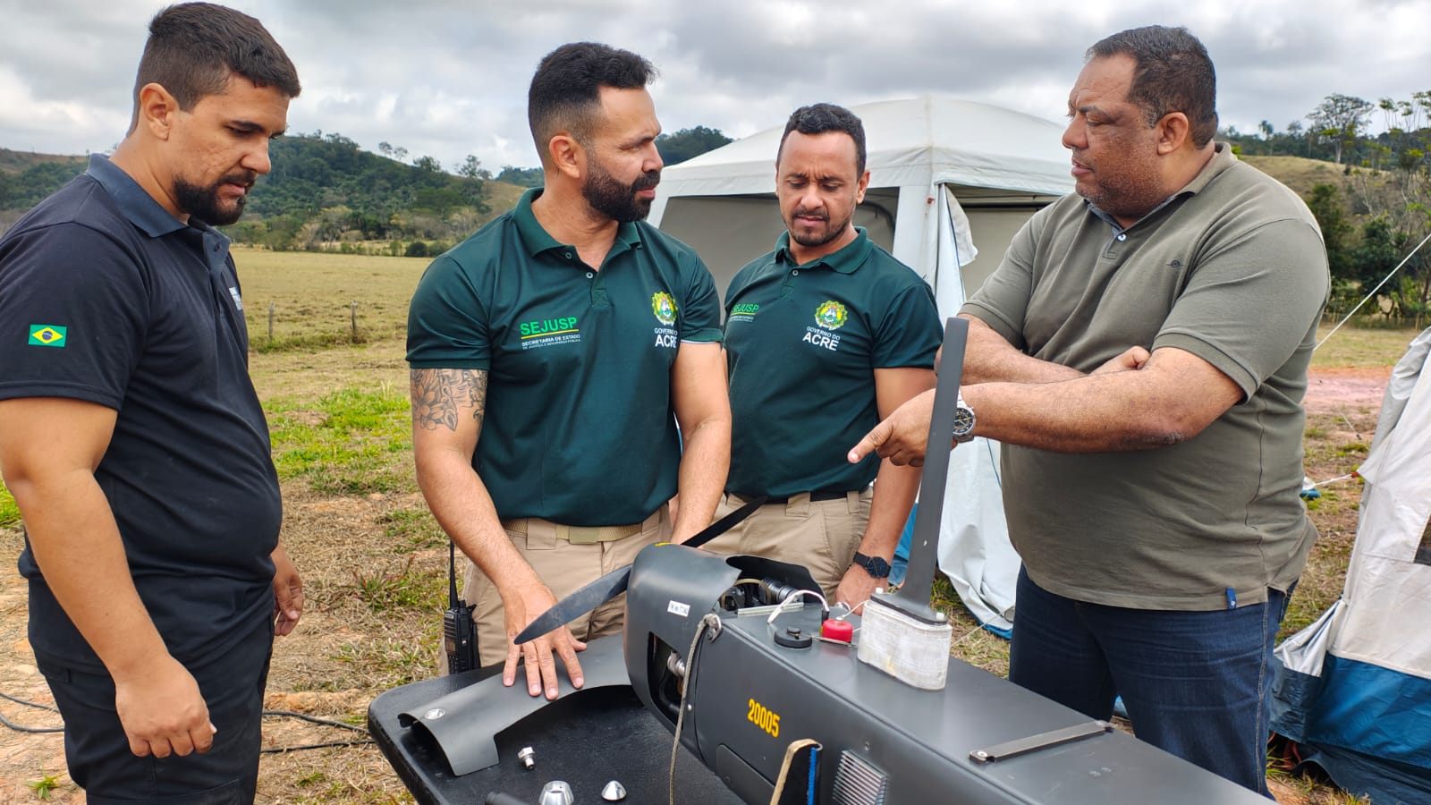 Homens discutem equipamento em ambiente rural.