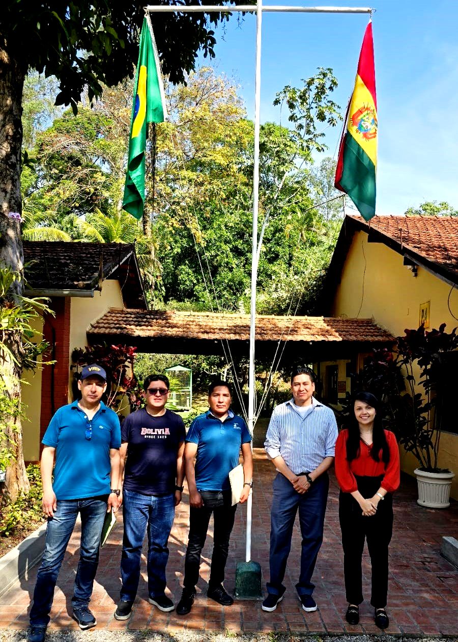 Cinco pessoas em frente a bandeiras do Brasil e Bolívia.