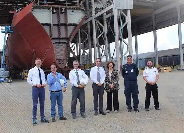 Pessoas posando em frente a navio em construção.