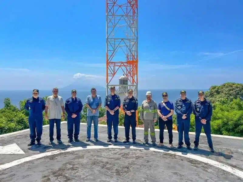 Grupo uniformizado em frente a torre de comunicação.