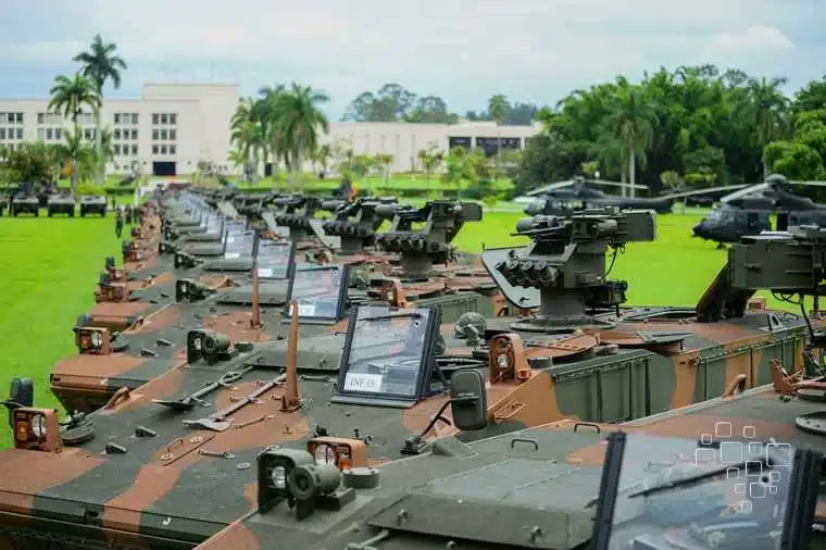 Veículos blindados militares enfileirados em área verde.