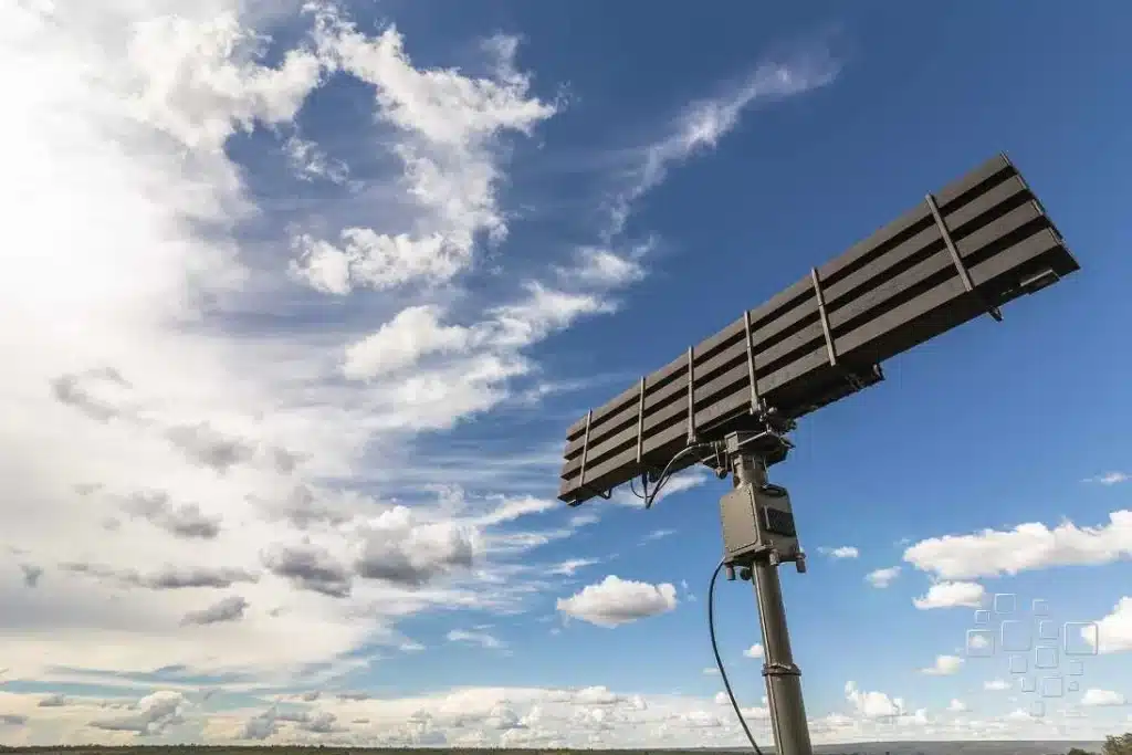 Radar contra céu azul com nuvens brancas.