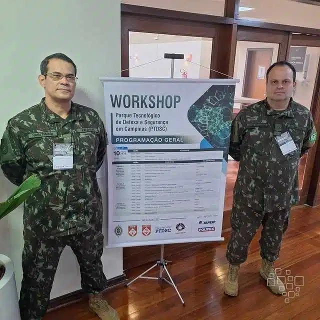 Dois militares ao lado de cartaz de workshop.