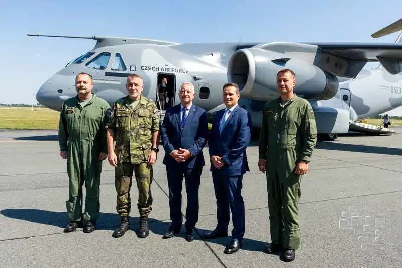 Pilotos e oficiais posando na frente de aeronave militar.
