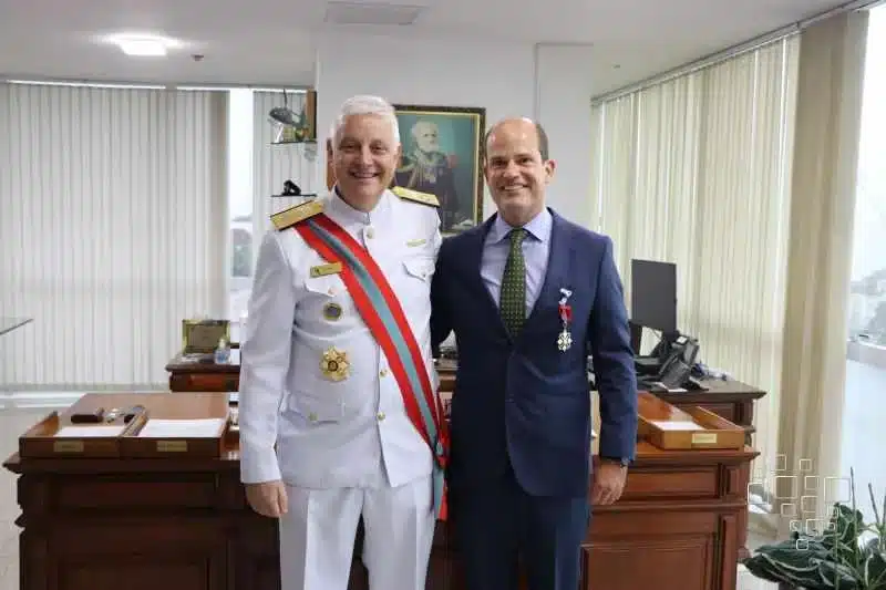 Dois homens uniformizados sorrindo em escritório.