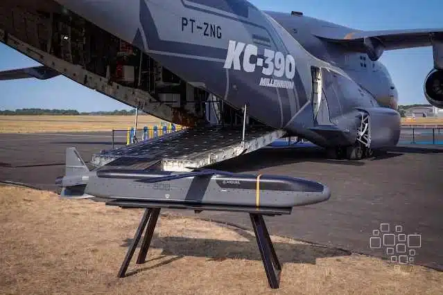 Avião militar KC-390 com míssil exposto, em aeroporto.