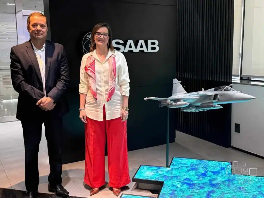 Executivos posam ao lado de um modelo de avião.