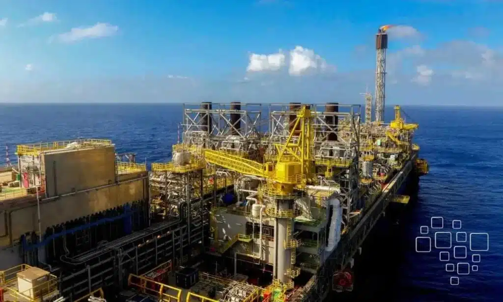 Plataforma de petróleo em mar aberto, céu azul.
