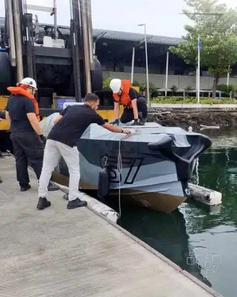 Barco sendo colocado na água por equipe.