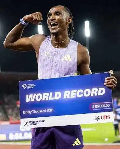 Atleta comemora recorde mundial com cheque prêmio.