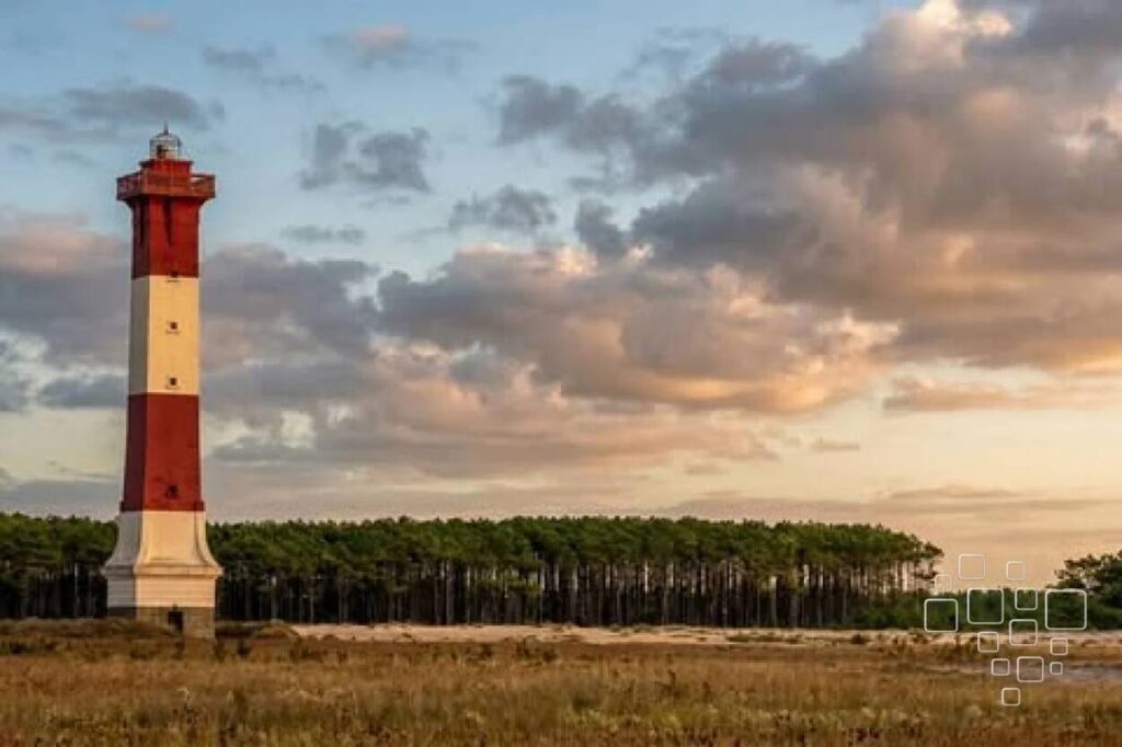 Farol vermelho e branco sob céu nublado.