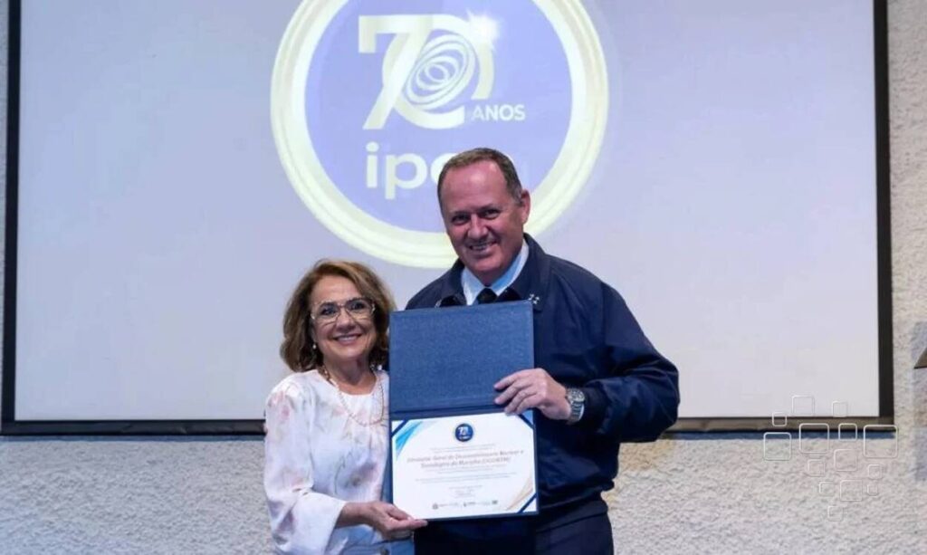 Duas pessoas recebem certificado no evento de 70 anos.