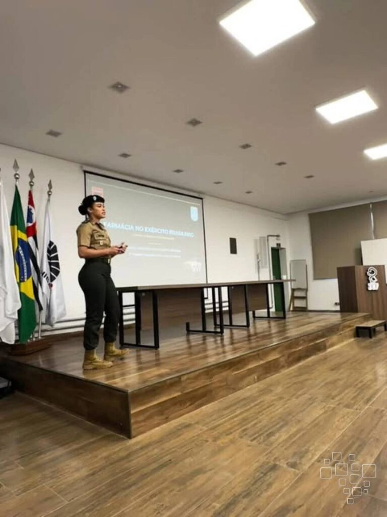 Palestrante no palco de auditório com bandeiras.