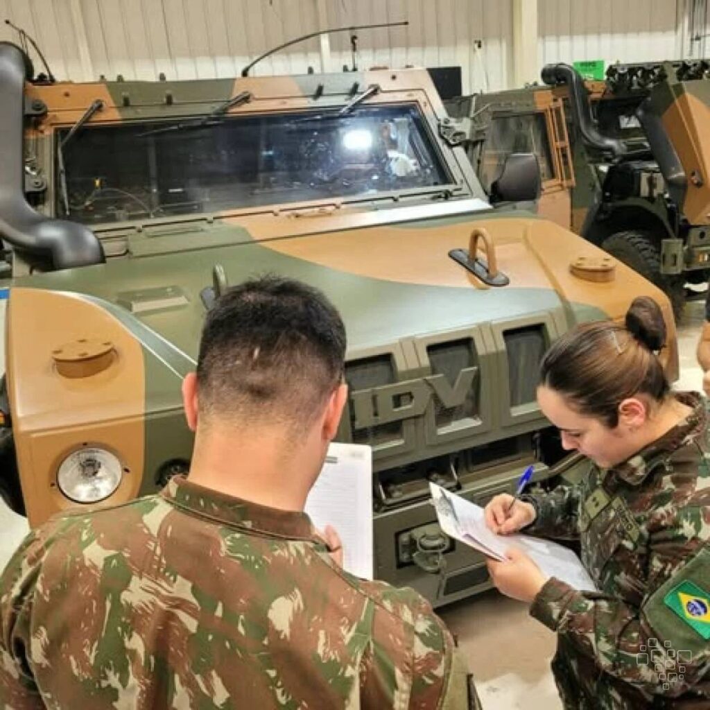 Militares inspecionam veículo blindado em garagem.