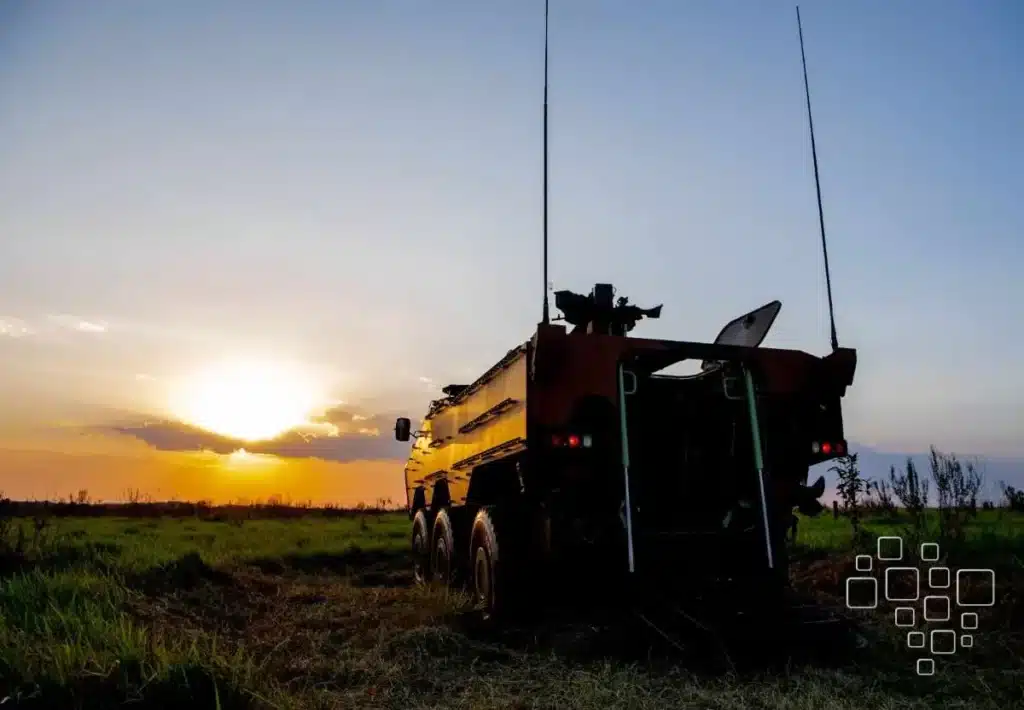 Veículo militar ao pôr do sol em campo aberto.